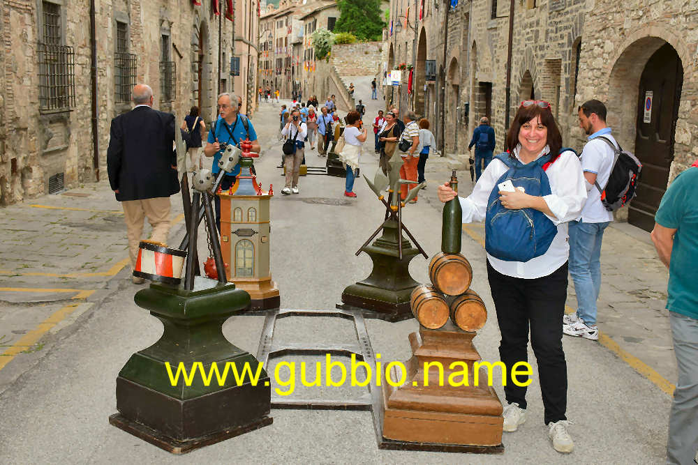 un tamburo con delle mazze, un'alabarda con le picche, dei barilotti con una bottiglia e una casa con delle botteghe